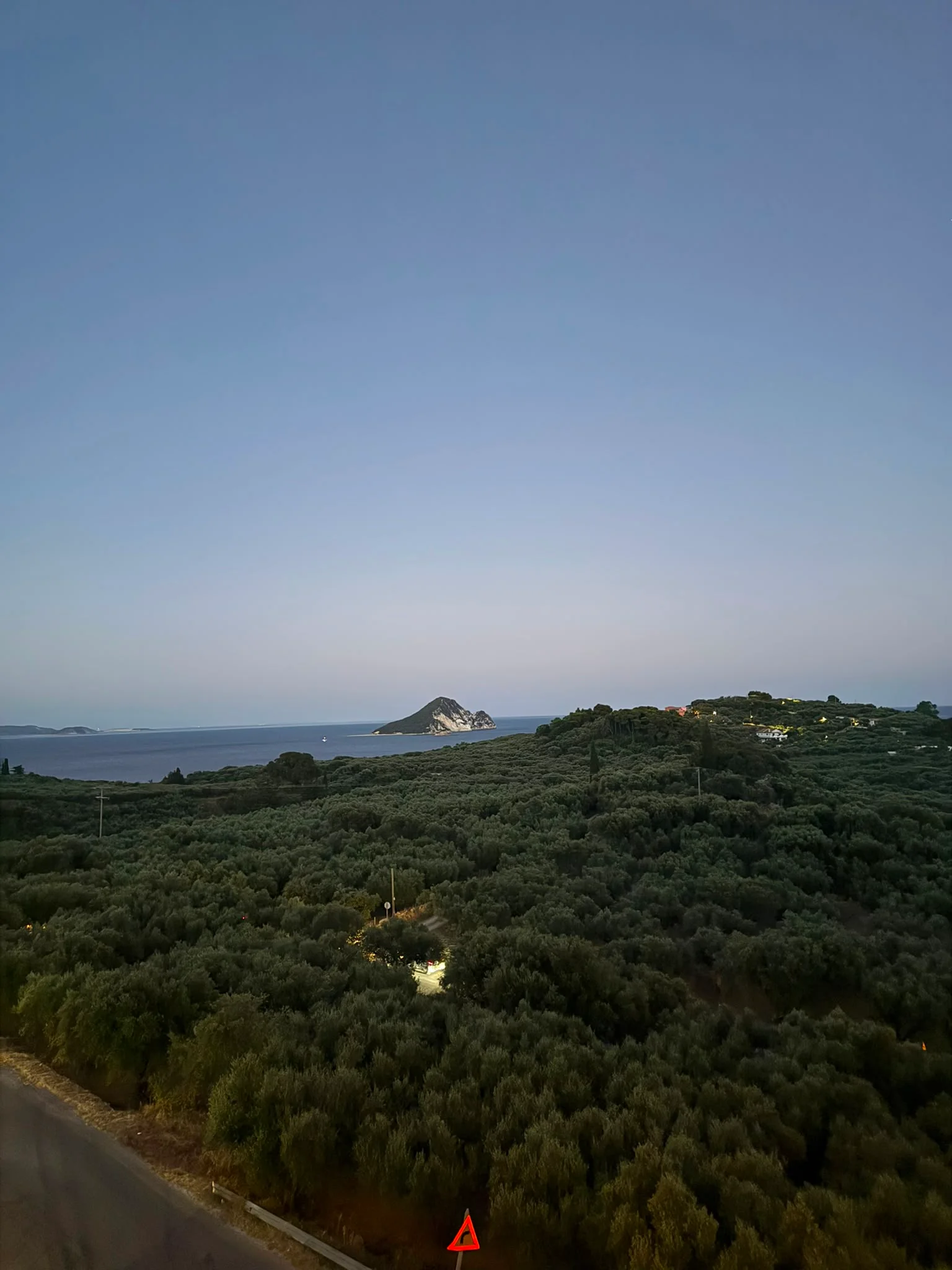 Dusk over the olive groves, looking out across the bay to a small offshore islet