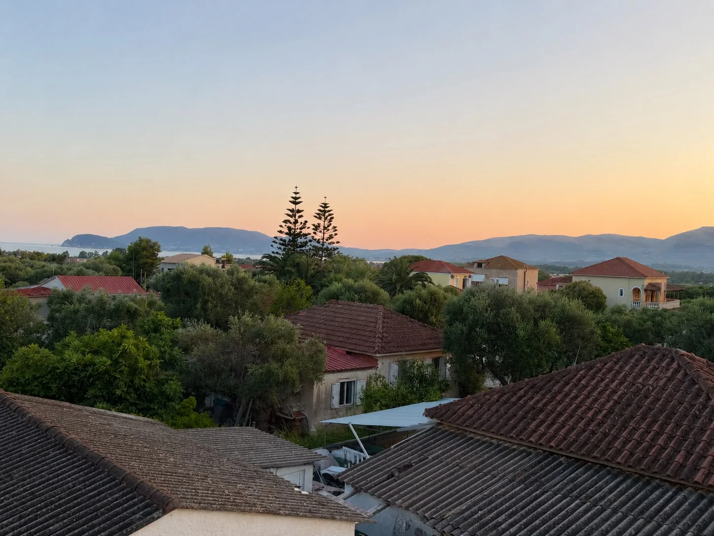 View from the balcony across the rooftops to Laganas Bay and the mountains at dusk